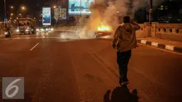 Pemilik mobil terdiam melihat mobilnya terbakar di jalan layang Latuharhari, Jakarta, Kamis (18/9/2015). Diduga kebakaran akibat konsleting listrik yang terjadi dibagian depan kap mobil. (Liputan6.com/Faizal Fanani)