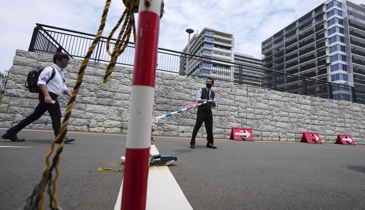 Karyawan mengenakan masker untuk mencegah penyebaran virus corona berjalan di lokasi pembangunan desa atlet yang akan digunakan selama Olimpiade dan Paralimpiade Tokyo 2020 di Tokyo (31/5/2021). Jepang mengkonfirmasi lebih dari 260 kasus virus corona baru pada hari Senin. (AP Photo/Eugene Hoshiko)