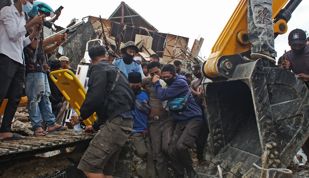 Tim penyelamat membantu korban yang ditarik keluar dari reruntuhan gedung pemerintah yang runtuh saat gempa bumi di Mamuju, Sulawesi Barat, Jumat (15/1/2021). Gempa bermagnitudo 6,2 mengguncang Mamuju, Sulawesi Barat. (AP Photo/Azhari Surahman)