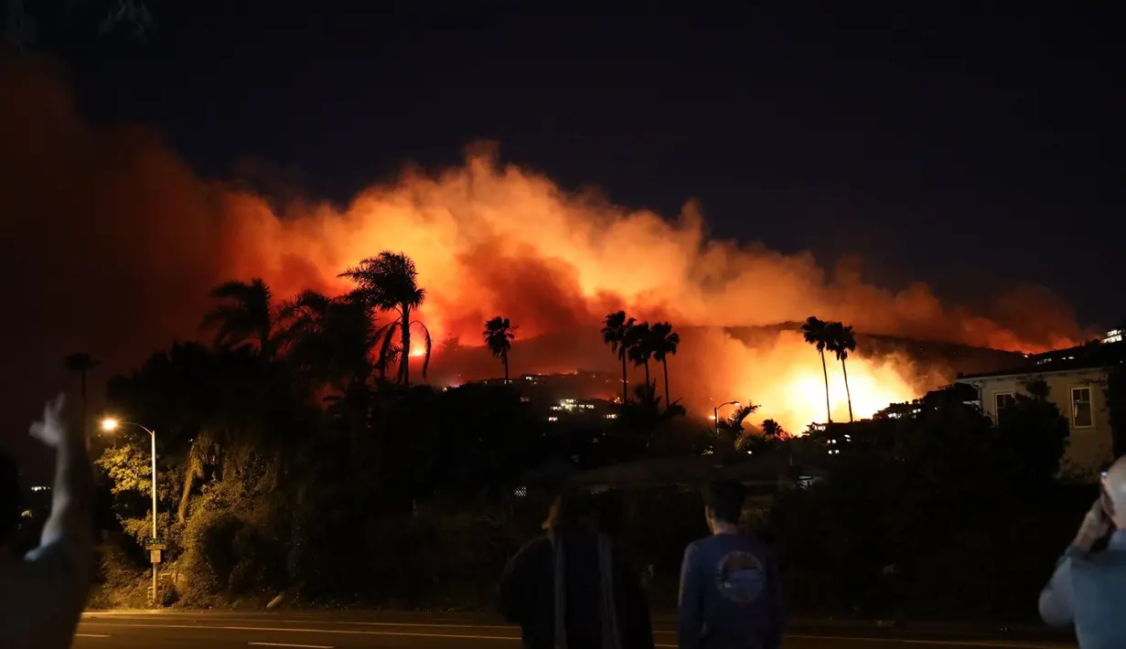 Warga melihat Kebakaran hutan yang di Emerald Bay Area dekat Pantai Laguna, California (10/2/2022). Petugas pemadam kebakaran tengah mencegah api merusak rumah. (@dustyschuh via AP)