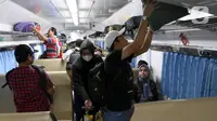 Penumpang menaikkan barang bawaan di dalam gerbong Kereta Api Jarak Jauh (KAJJ) di Stasiun Pasar Senen, Jakarta, Rabu (26/3/2025). (Liputan6.com/Herman Zakharia)