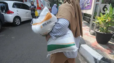 Warga berjalan dengan membawa beras kemasan 10 kilogram di Kelurahan Pela Mampang, Jakarta, Jumat (3/5/2024). (merdeka.com/Imam Buhori)