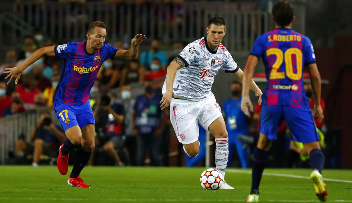 Pemain Bayern Munhen Niklas Suele (tengah) berebut bola dengan pemain Barcelona Luuk de Jong pada pertandingan Grup E Liga Champions di Stadion Camp Nou, Barcelona, Spanyol, Selasa (14/9/2021). Bayern Munchen menang 3-0. (AP Photo/Joan Monfort)