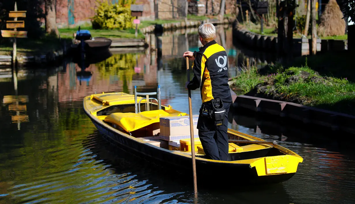 Tukang pos wanita dari Deutsche Pos DHL, Andrea Bunar menggunakan perahu tradisional mengantar surat dan paket di desa Spreewald di Lehde, Jerman, 4 April 2019. Andrea Bunar mengantarkan surat lewat sungai karena banyak rumah-rumah warga yang tak terjangkau lewat darat. (REUTERS/Hannibal Hanschke)