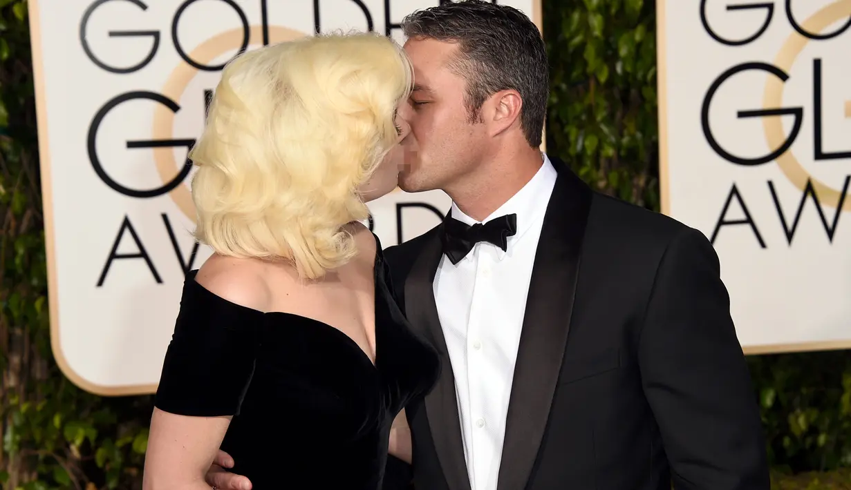 Penyanyi Lady Gaga dan sang tunangan, Taylor Kinney saling berciuman dengan mesra saat ditengah-tengah sesi foto ajang penghargaan film tahunan, Golden Globes 2016 di Beverly Hilton Hotel, California, Minggu (10/1). (Jason Merritt/Getty Images/AFP)