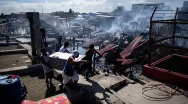 Sejumlah warga membawa barang miliknya saat rumah-rumah mereka hangus terbakar di sebuah daerah kumuh di Navotas, Manila (8/11). Dilaporkan sekitar 150 keluarga terkena dampak kebakaran tersebut. (AFP Photo/Noel Celis)