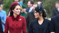 Duchess of Cambridge, Kate Middleton dan Duchess of Sussex, Meghan Markle berbincang saat menghadiri perayaan Natal kerajaan di Gereja St Mary Magdalene di Sandringham, Inggris (25/12). Keduanya tampil cantik mengenakan gaun. (AFP Photo/Paul Ellis)