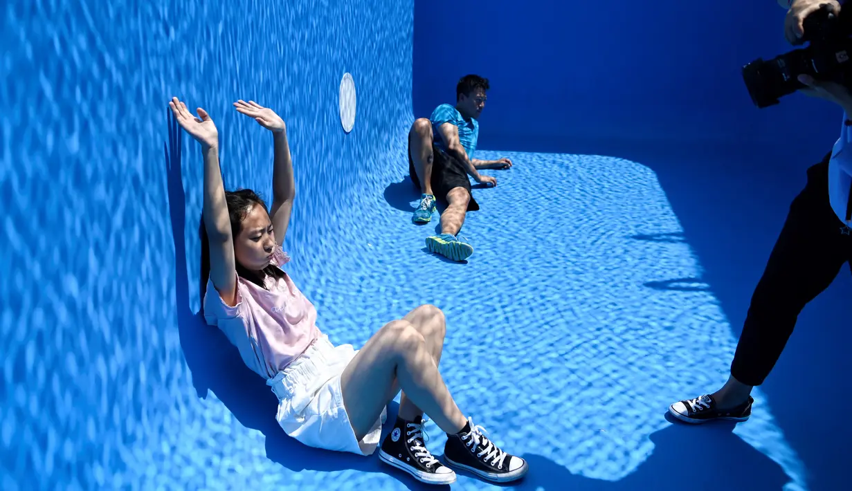 Pengunjung berfoto di karya seni Swimming Pool dalam sebuah pameran pameran bertajuk "The Confines of the Great Void" di Museum CAFA, Beijing, 23 Juli 2019. Karya seni buatan seniman Argentina, Leandro Erlich ini tampak seperti kolam renang pada umumnya yang penuh dengan air. (WANG Zhao/AFP)