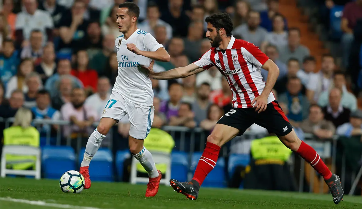 Pemain Real Madrid, Lucas Vazquez berebut bola dengan pemain Athletic Bilbao, Raul Garcia pada pekan ke-33 La Liga di Santiago Bernabeu, Rabu (18/4). Real Madrid kembali meraih hasil minor usai bermain imbang 1-1 lawan Atletico Bilbao. (AP/Francisco Seco)