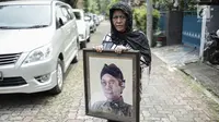 Seorang wanita memegang foto aktor senior Deddy Sutomo di dekat rumah duka kawasan Rempoa, Tangerang Selatan, Rabu (18/4). Selain berakting, Deddy Sutomo sempat menjadi anggota legislatif DPR RI komisi X periode 2004-2009. (Liputan6.com/Faizal Fanani)