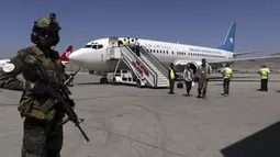 Seorang tentara Taliban berjaga-jaga ketika penumpang turun dari Kandahar, di Bandara Internasional Hamid Karzai di Kabul, Afghanistan, Minggu (5/9/2021). Bandara tersebut kembali dibuka untuk penerbangan domestik. (AP/Wali Sabawoon)