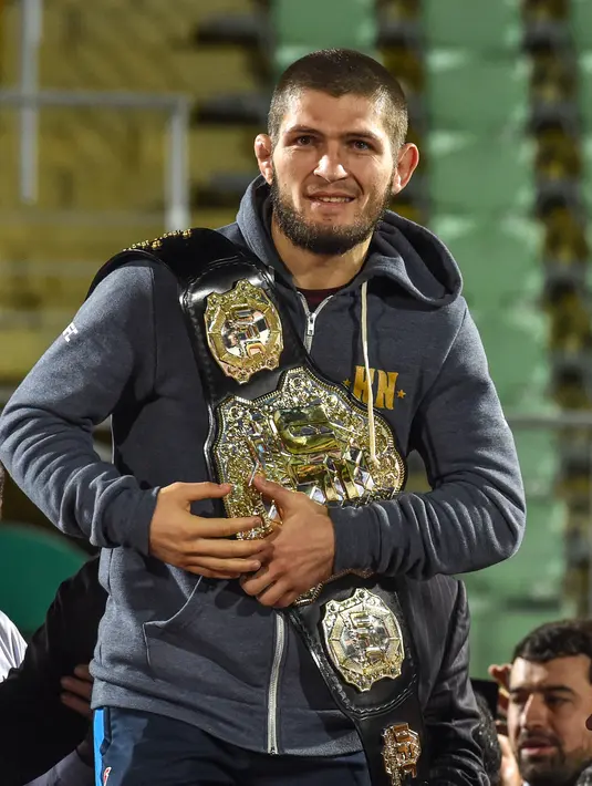 Juara kelas ringan UFC, Khabib Nurmagomedov membawa sabuk juaranya saat disambut oleh para penggemar setibanya di Makhachkala, Rusia, Senin (8/10). Nama Khabib menjadi terkenal setelah dirinya berhasil mengalahkan Conor McGregor. (AFP/Vasily MAXIMOV)
