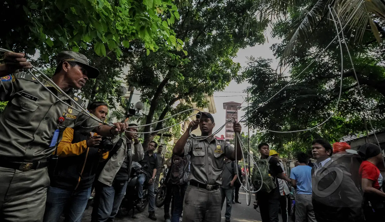 Petugas PLN dibantu Satpol PP menertibkan sambungan listrik liar di Johar Baru, Jakarta, Rabu (25/3/2015). Kegiatan itu untuk mengurangi saluran listrik ilegal dan mencegah kebakaran. (Liputan6.com/Faizal Fanani)