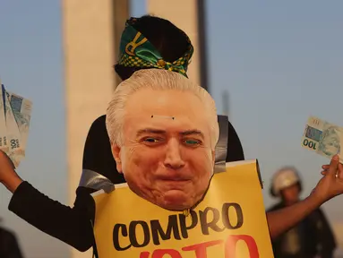 Seorang wanita memegang uang palsu dan poster bergambar Presiden Brasil Michel Temer pada unjuk rasa di depan Kongres Nasional, Brasilia, Rabu (2/8). Para demonstran membanjiri jalanan kota sejak Rabu waktu setempat. (AP/Eraldo Peres)