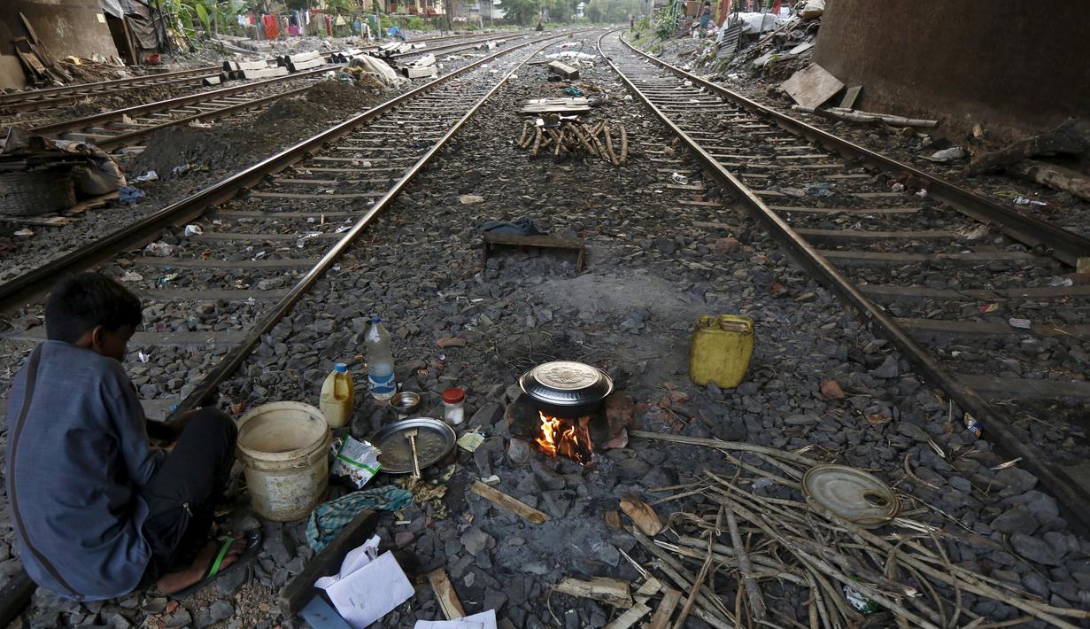 Ratan Samanta (29) tengah memasak diantara rel kereta api di Kolkata, India, 13 Maret 2016. Beberapa orang di Kolkata bekerja sebagai penjual pakaian bekas atau pengemudi becak dan mereka terlalu miskin untuk membeli rumah. (REUTERS/Rupak De Chowdhuri)