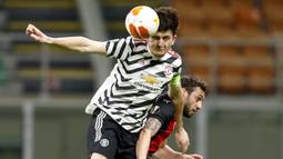 Bek Manchester United, Harry Maguire (depan) berduel udara dengan gelandang AC Milan, Hakan Calhanoglu dalam laga leg kedua babak 16 besar Liga Europa 2020/2021 di San Siro Stadium, Milan, Kamis (18/3/2021). Manchester United menang 1-0 atas AC Milan. (AP/Antonio Calanni)
