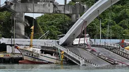 Sebuah kapal nelayan tertimpa jembatan beton yang ambruk di pelabuhan ikan Nanfangao di kota Suao (1/10/2019). Kejadian tersebut membuat setidaknya 14 orang terluka. (AFP Photo/Sam Yeh)