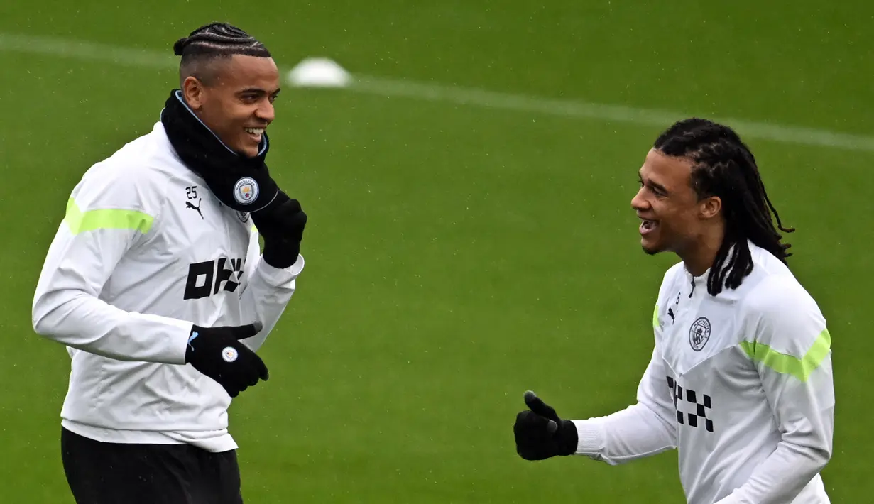 Pemain Manchester City Manuel Akanji (kiri) dan Nathan Ake tertawa saat menjalani sesi latihan tertawa saat menjalani sesi latihan di tempat latihan Manchester City di Manchester, Inggris, 13 Maret 2023. Manchester City akan menghadapi RB Leipzig pada pertandingan sepak bola leg kedua babak 16 besar Liga Champions. (Paul ELLIS/AFP)