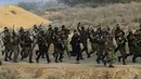 Militan Palestina dengan wajah dicat berbaris dengan senjata mereka dan meneriakkan slogan-slogan selama latihan militer yang diselenggarakan oleh faksi-faksi militer di Rafah, Jalur Gaza selatan, Rabu (29/12/2021). (AP Photo/Adel Hana)