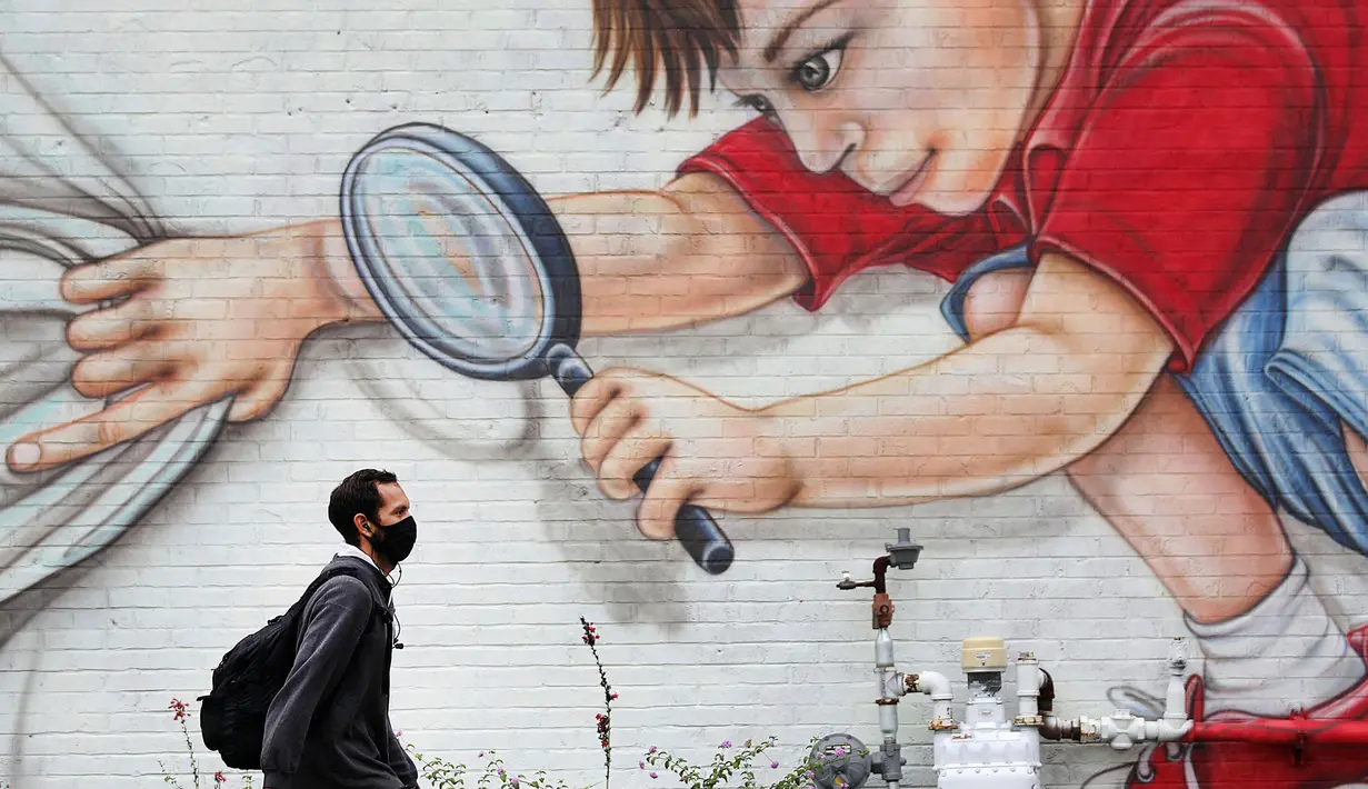 Johnny Lopez melewati mural di sisi Hideaway Pizza di Rockford Ave sambil berjalan pulang dari kantor di Tulsa, Oklahoma pada 10 September 2020. (Mike Simons/Tulsa World via AP)