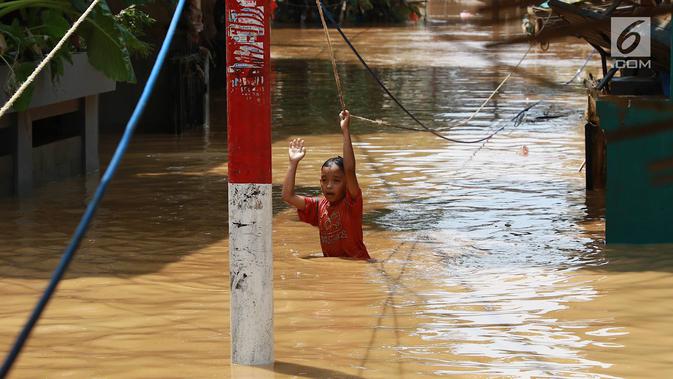 Seorang anak melintasi banjir yang menggenangi kawasan Pejaten Timur, Jakarta, Jumat (26/4). Banjir yang berasal dari luapan Sungai Ciliwung tersebut merendam ratusan rumah warga hingga kedalaman lebih dari satu meter. (Liputan6.com/Immanuel Antonius)