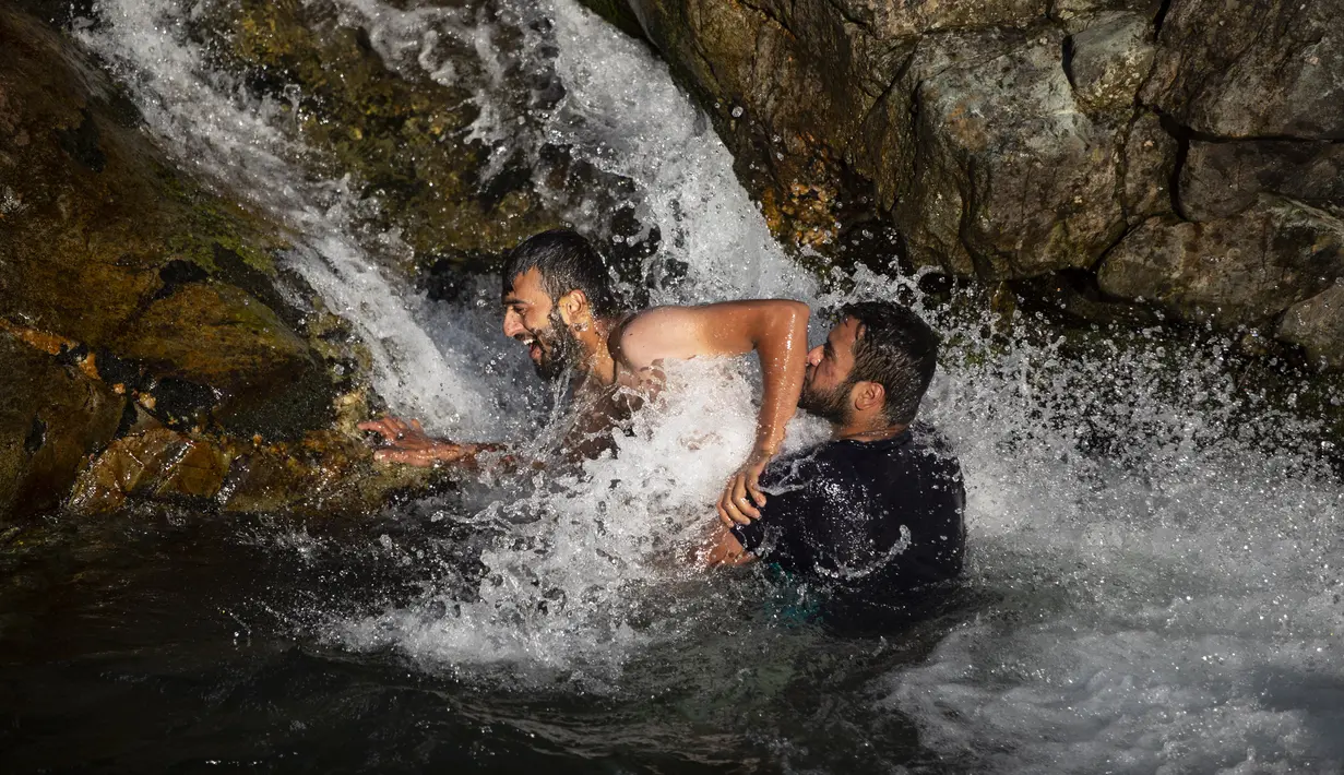 Dua pria bermain air di sungai saat musim panas di pinggiran Srinagar, Kashmir yang dikuasai India (4/7/2021). Musim panas waktu yang tepat untuk menghabiskan waktu di ruang terbuka hijau. Seperti warga Kashmir menikmati musim panas dengan pergi ke sungai. (AP Photo/Mukhtar Khan)
