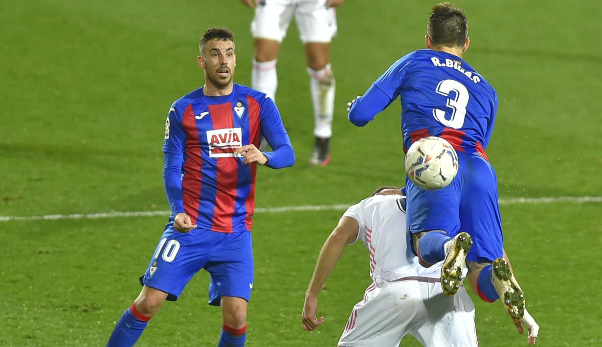 Bek Eibar Pedro Bigas (kanan) menantang penyerang Real Madrid Karim Benzema pada laga lanjutan Liga Spanyol di Stadion Ipurua, Senin dinihari WIB (21/12/2020). Karim Benzema menjadi pahlawan dalam kemenangan Madrid karena menciptakan satu gol dan dua assist di laga tersebut. (ANDER GILLENEA/AFP)