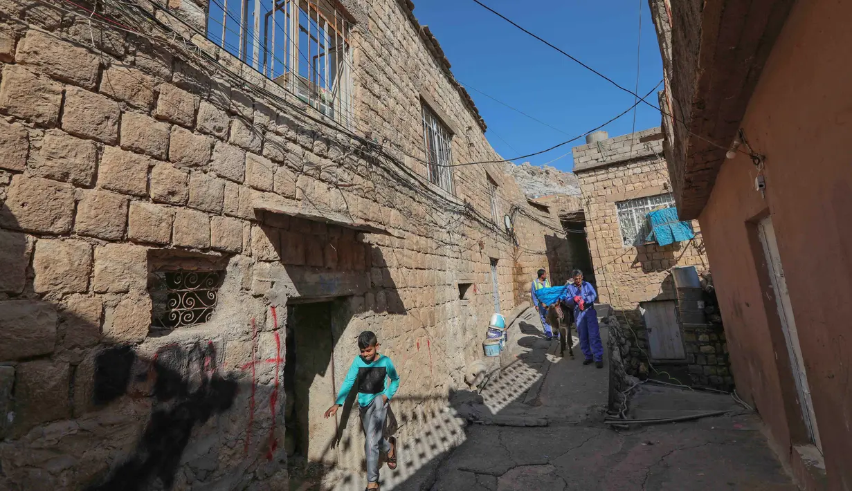 Seorang pekerja kota tiba dengan keledai untuk mengumpulkan sampah rumah tangga di kota Akre, sekitar 500 km sebelah utara Baghdad, Irak, 13 Februari 2021. Keledai dan anak kuda digunakan untuk mengumpulkan sampah di gang-gang yang terlalu sempit dilalui truk atau kendaraan lain. (SAFIN HAMED/AFP)