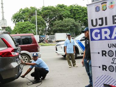 Petugas melakukan uji emisi kendaraan di kawasan Jalan Perintis Kemerdekaan, Kelapa Gading, Jakarta Utara, Selasa (3/12/2024). (Liputan6.com/Herman Zakharia)