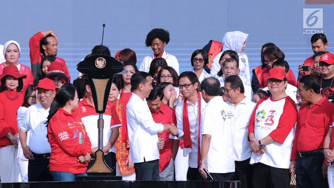 Presiden RI, Joko Widodo (tengah) menyalami konduktor Addie MS jelang bernyanyi bersama peserta Harmoni Indonesia 2018 di Kompleks Gelora Bung Karno, Jakarta, Minggu (5/8). Acara ini bagian perayaan HUT RI ke-73. (Liputan6.com/Helmi Fithriansyah)