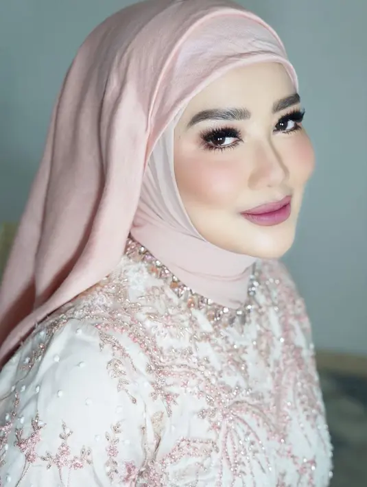 Seperti potret ini, Reza tampil menawan dengan dress berhiaskan bordir dan hijab nuansa baby pink.  [@rezaartameviaofficial]