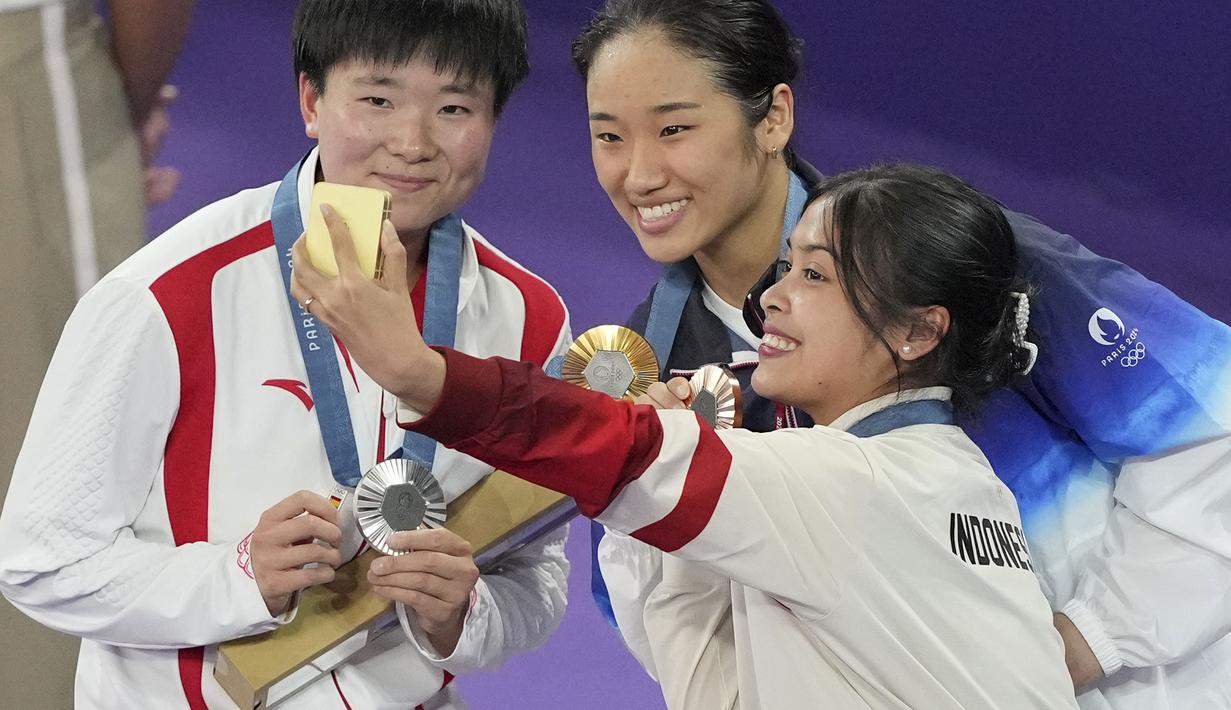 Pebulu tangkis tunggal putri China, He Bing Jiao (kiri) berswafoto dengan pebulu tangkis Korea Selatan, An Se-young (tengah) dan pebulu tangkis Indonesia, Gregoria Mariska Tunjung di atas podium Olimpiade Paris 2024 setelah laga final yang berlangsung di Porte de la Chapelle Arena, Paris, Prancis, Senin (05/08/2024). (AP Photo/Dita Alangkara)