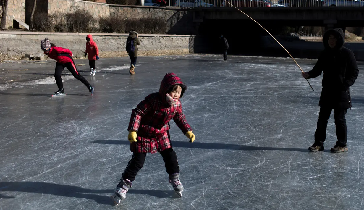 Seorang anak saat bermain ice skating di sungai yang membeku di Beijing, China (21/1). Akibat membeku, Sungai ini menjadi objek wisata dadakan yang banyak diminati wisatawan. (AFP/Fred Dufour)