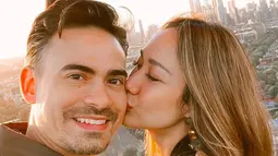 Penyanyi Bunga Citra Lestari mencium suaminya Ashraf Sinclair saat menaiki balon udara di Melbourne. Suami Bunga Citra Lestari, Ashraf Sinclair, meninggal dunia di usia 40 tahun diduga akibat serangan jantung pada Selasa 18 Februari 2020 pukul 3.40 pagi. (Instagram/@bclsinclair)