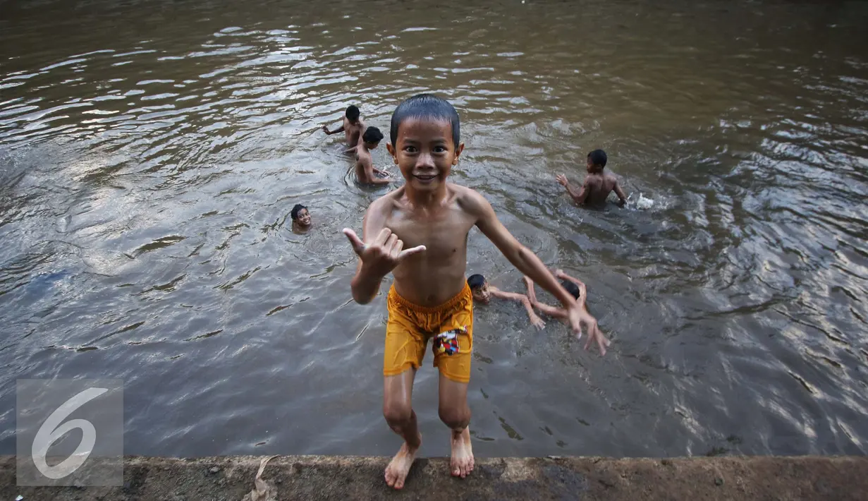 Sejumlah anak mandi di Sungai Ciliwung, Jakarta, Rabu (16/11). Cuaca panas di Jakarta membuat anak-anak tersebut mandi di sungai untuk mendinginkan suhu tubuh. (Liputan6.com/Gempur M Surya)