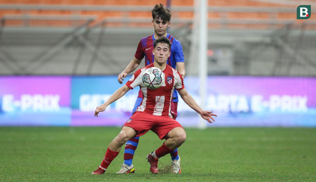 Pemain Atletico Madrid U-18, Jose Manuel Ordonez Elola (depan) berebut bola dengan pemain Barcelona U-18, Ricard Pulido Romera saat laga International Youth Championship 2021 di Jakarta International Stadium, Jakarta, Jumat (15/04/2022). (Bola.com/Bagaskara Lazuardi)