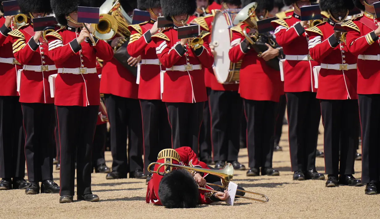 Seorang trombonis militer yang pingsan tampaknya berusaha untuk terus bermain setelah jatuh ke tanah saat petugas medis bergegas membantunya. (AP Photo/Alberto Pezzali)