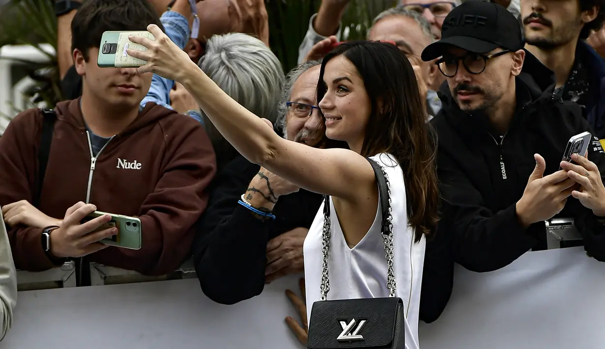 Ana de Armas berselfie dengan para penggemar setelah tiba di Festival Film San Sebastian ke-70, di San Sebastian, Spanyol utara (23/9/2022). Di film Blonde, Ana memerankan sosok Marilyn Monroe. (AP Photo/Alvaro Barrientos)