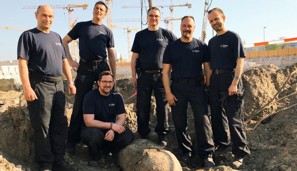 Tim penjinak bom berpose dengan bom perang dunia II saat ditemukan di Berlin, Jerman, Jumat (20/4). Bom yang ditemukan oleh pekerja konstruksi tersebut masih dalam kondisi aktif. (Polizei Berlin via AP)
