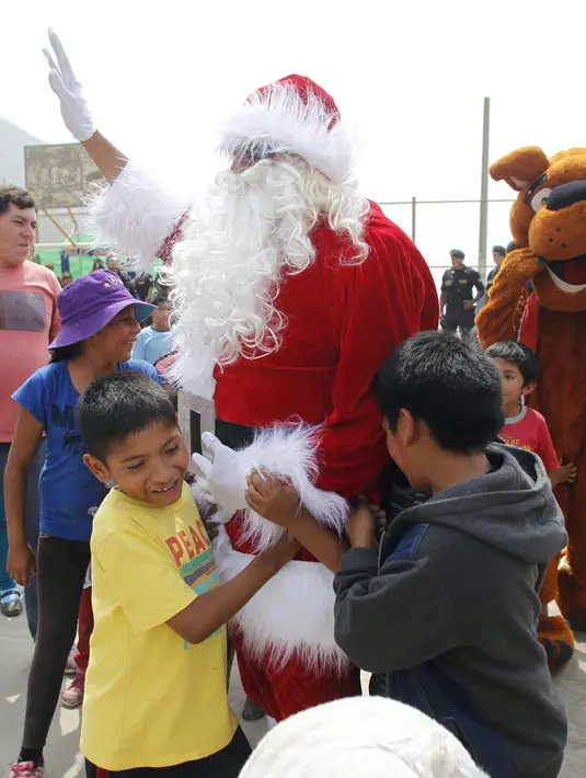 Seorang polisi Peru berpakaian seperti Santa Claus bermain dengan anak-anak selama perayaan Natal di Huaycan, Lima, Peru (15/12/2015). (REUTERS/Janine Costa)