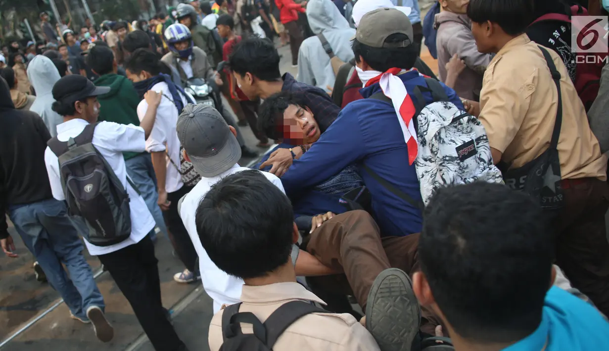 Sejumlah pelajar menggotong rekan mereka yang terluka dalam demonstrasi di belakang Gedung DPR, Palmerah, Jakarta, Rabu (25/9/2019). Pelajar bahu membahu membantu rekan mereka yang terluka dalam demonstrasi. (Liputan6.com/Angga Yuniar)