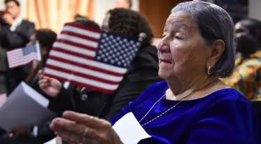 Maria Valles Bonilla melambaikan bendera AS selama upacara naturalisasi di kantor Citizenship and Immigration Services AS (USCIS) di Fairfax, Virginia, 6 November 2018. Nenek 106 tahun itu resmi menjadi warga negara Amerika Serikat. (MANDEL NGAN/AFP)