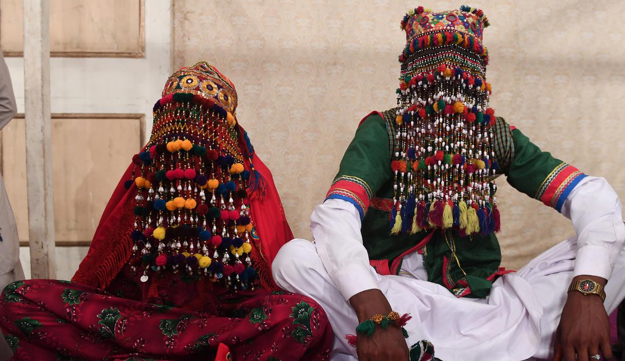 Sepasang pengantin mengenakan baju tradisional saat menjalani prosesi pernikahan massal di Karachi, Pakistan, (19/3). Sebanyak 62 pasangan pengantin mengikuti pernikahan massal yang merupakan bagian dari perayaan Festival Holi.  (AFP Photo /Asif Hassan)