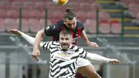 Pemain AC Milan Zlatan Ibrahimovic melompat di atas pemain Manchester United Luke Shaw untuk menyundul bola ke gawang pada pertandingan leg kedua babak 16 besar Liga Europa di Stadion San Siro, Milan, Italia, Kamis (18/3/2021). Manchester United  menang 1-0. (AP Photo/Antonio Calanni)