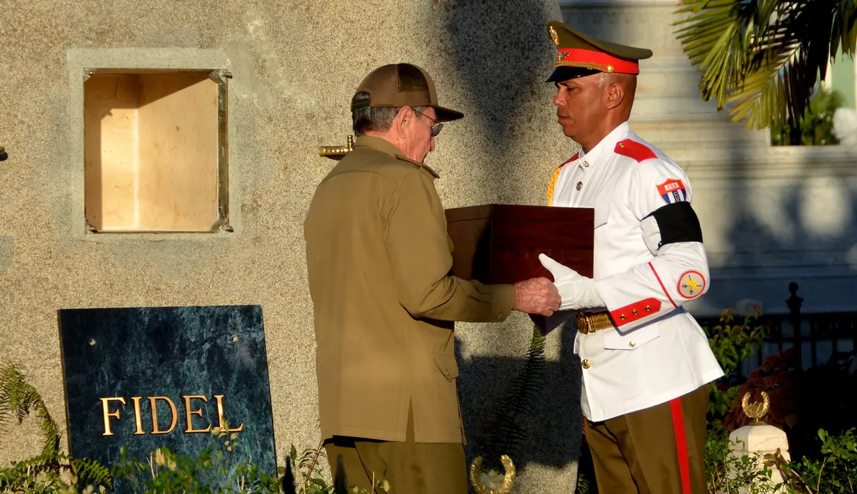 Presiden Kuba, Raul Castro (kiri) menerima kotak kayu berisi abu mantan Presiden Kuba, Fidel Castro saat akan dimakamkan di peristirahatan terakhir di Santa Ifigenia Cemetery, di Santiago, Kuba (4/12). (REUTERS/ACN/Marcelino Vazquez)