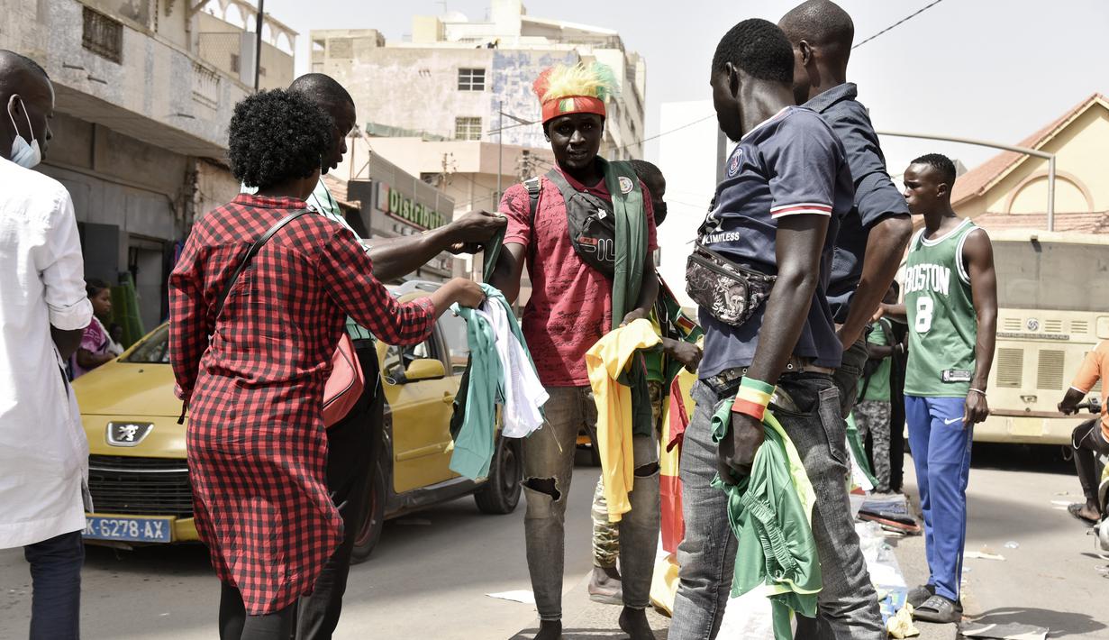Seorang pedagang kaki lima menjual kaus timnas Senegal di Dakar (4/2/2022). Senegal akan bertanding melawan Mesir pada babak final Piala Afrika 2021 di Paul Biya stadium, Senin (7/2/2022) dini hari WIB besok. (AFP/Seyllou)