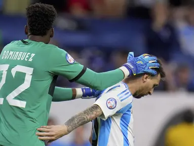 Kiper Ekuador Alexander Dominguez menghibur penyerang Argentina Lionel Messi setelah tembakannya gagal saat adu penalti  pada laga perempat final Copa America 2024 di NRG Stadium, Jumat (5/7/2024) pagi WIB. (AP Photo/Julio Cortez)
