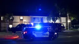 Petugas polisi berdiri di luar gedung perkantoran, beberapa orang tewas dalam penembakan di Orange, California (31/3/2021).  Pihak berwenang mengatakan bahwa empat orang, termasuk seorang anak, tewas dalam penembakan dan dua lainnya telah diangkut ke rumah sakit setempat. (AFP/Patrick T. Fallon)