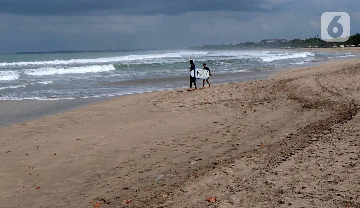 Wisatawan usai bermain selancar di kawasan Pantai Kuta, Bali, Jumat (3/9/2021). Sepinya wisatawan yang datang ke Pulau Bali selama PPKM Darurat yakni hanya sebesar rata-rata 500 wisatawan lokal menyebabkan sejumlah tempat wisata pantai sepi pengunjung. (merdeka.com/Arie Basuki)