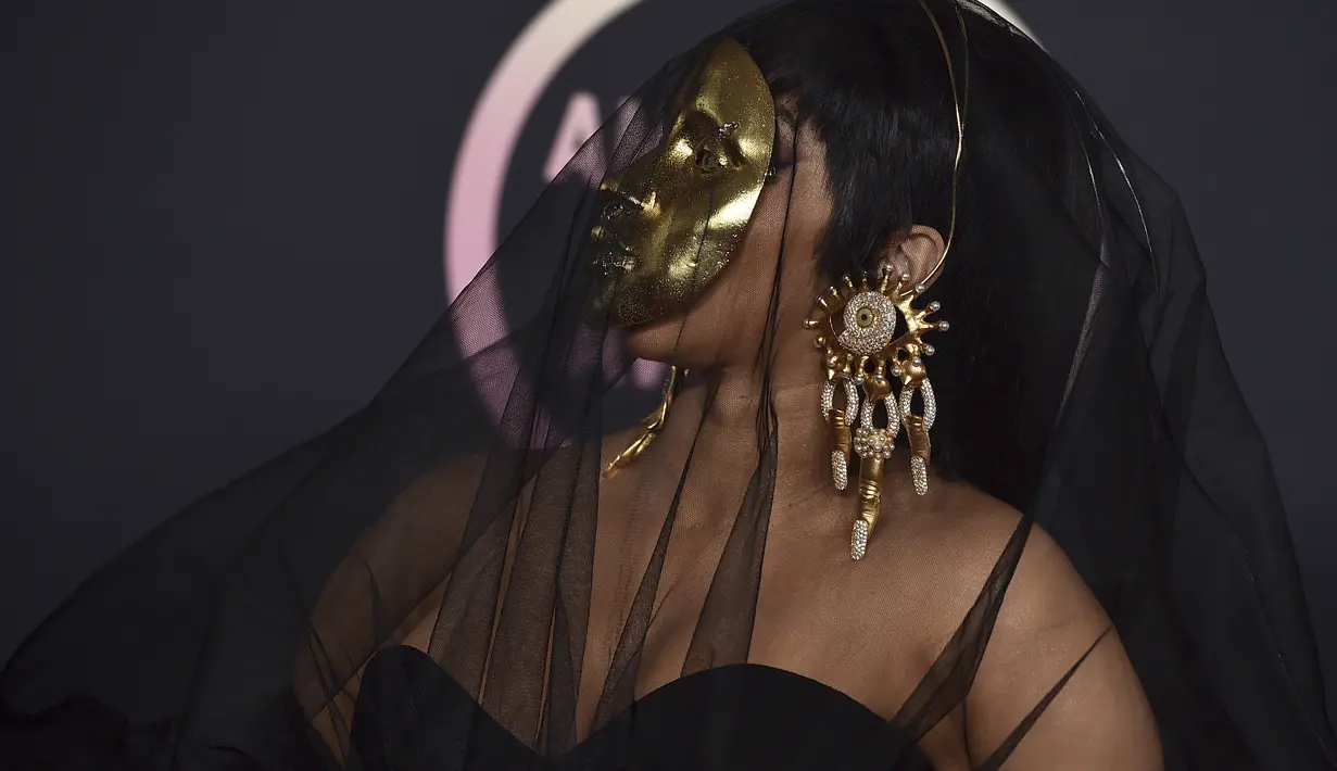 Cardi B tiba di American Music Awards di Microsoft Theater di Los Angeles (22/11/20210). Topeng emas mencoloknya tersebut, ia padukan bersama gaun strapless hitam rancangan Schiaparelli. (AP Photo/Jordan Strauss)